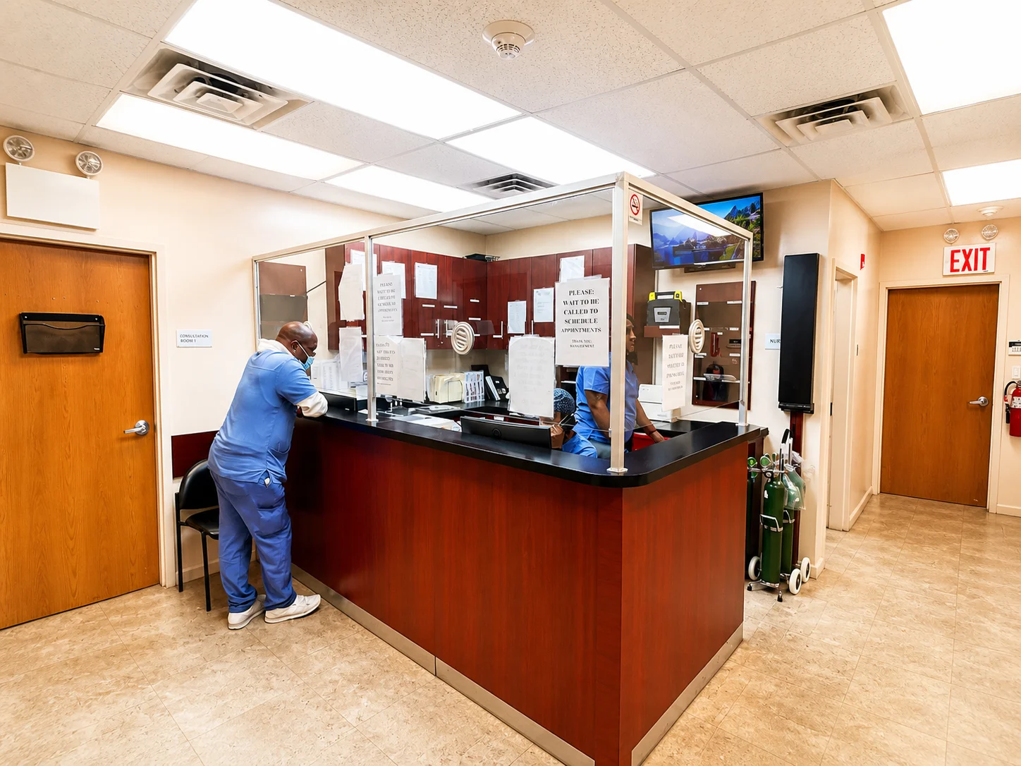 Front desk staff assisting a patient at Be Well Primary Health Care Center
